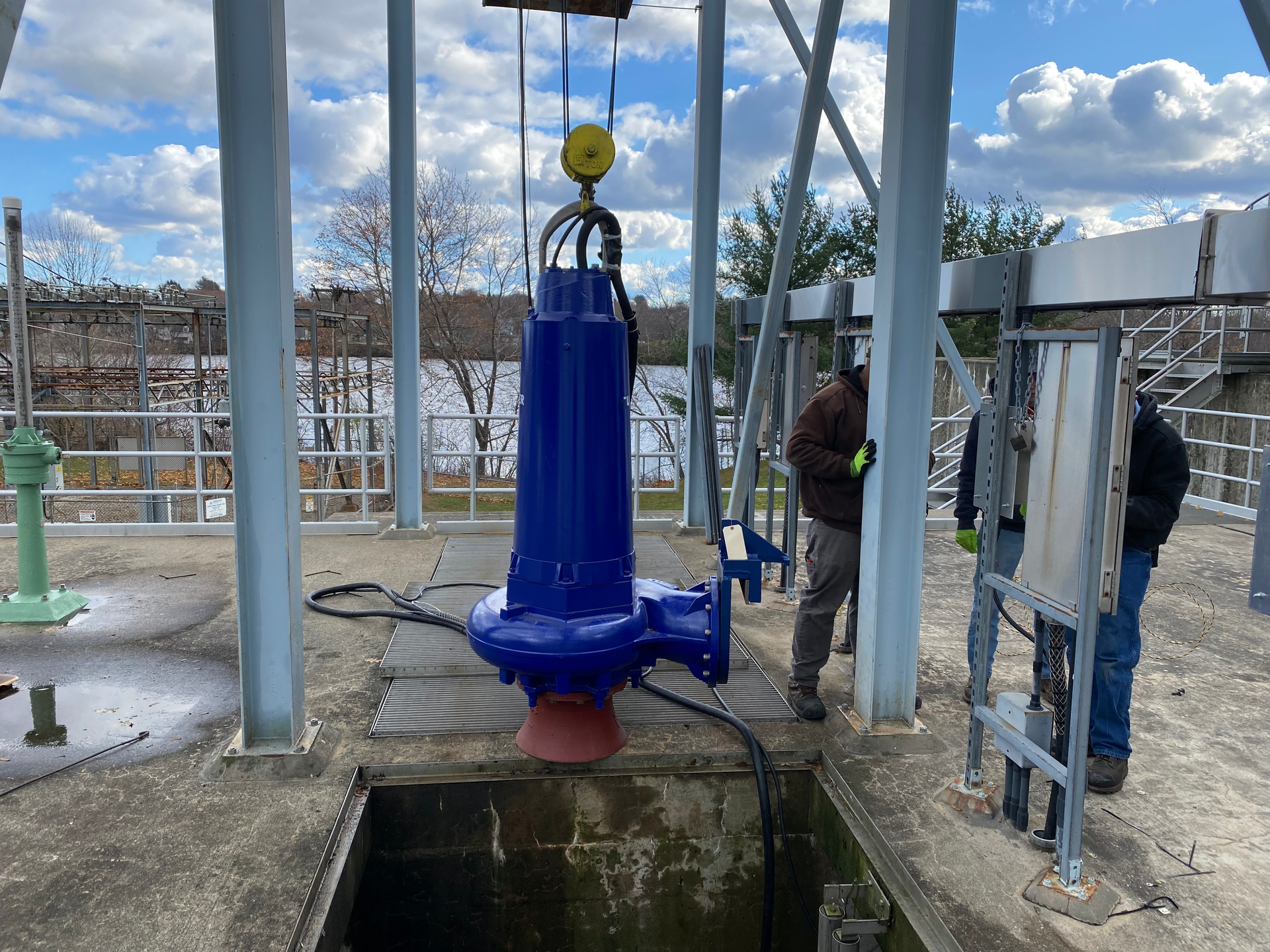 A man is standing next to a large blue pump.