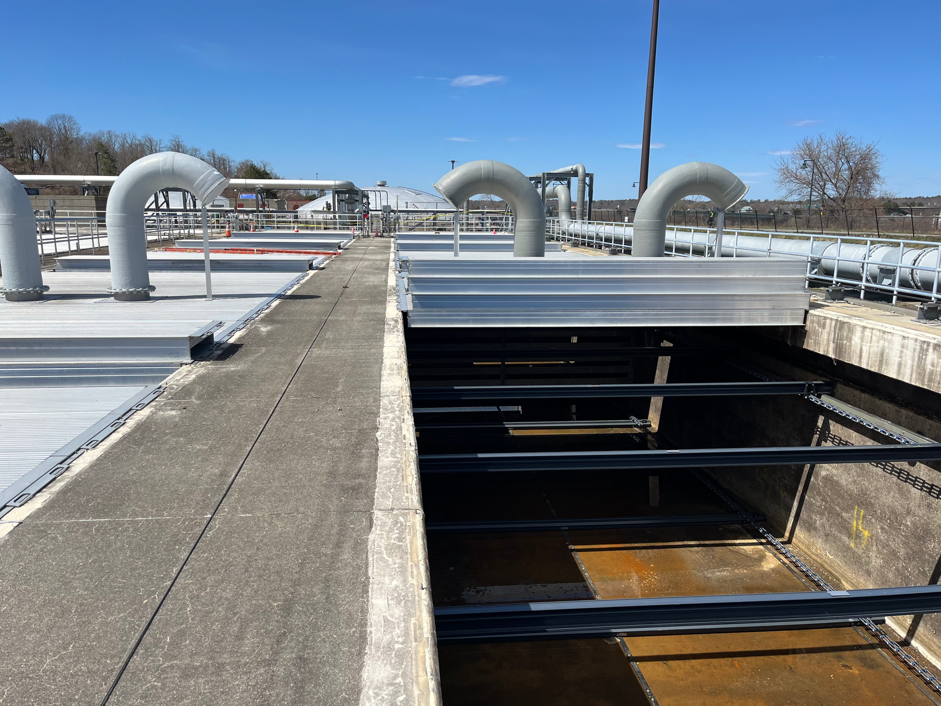 A concrete walkway with pipes on the side of it