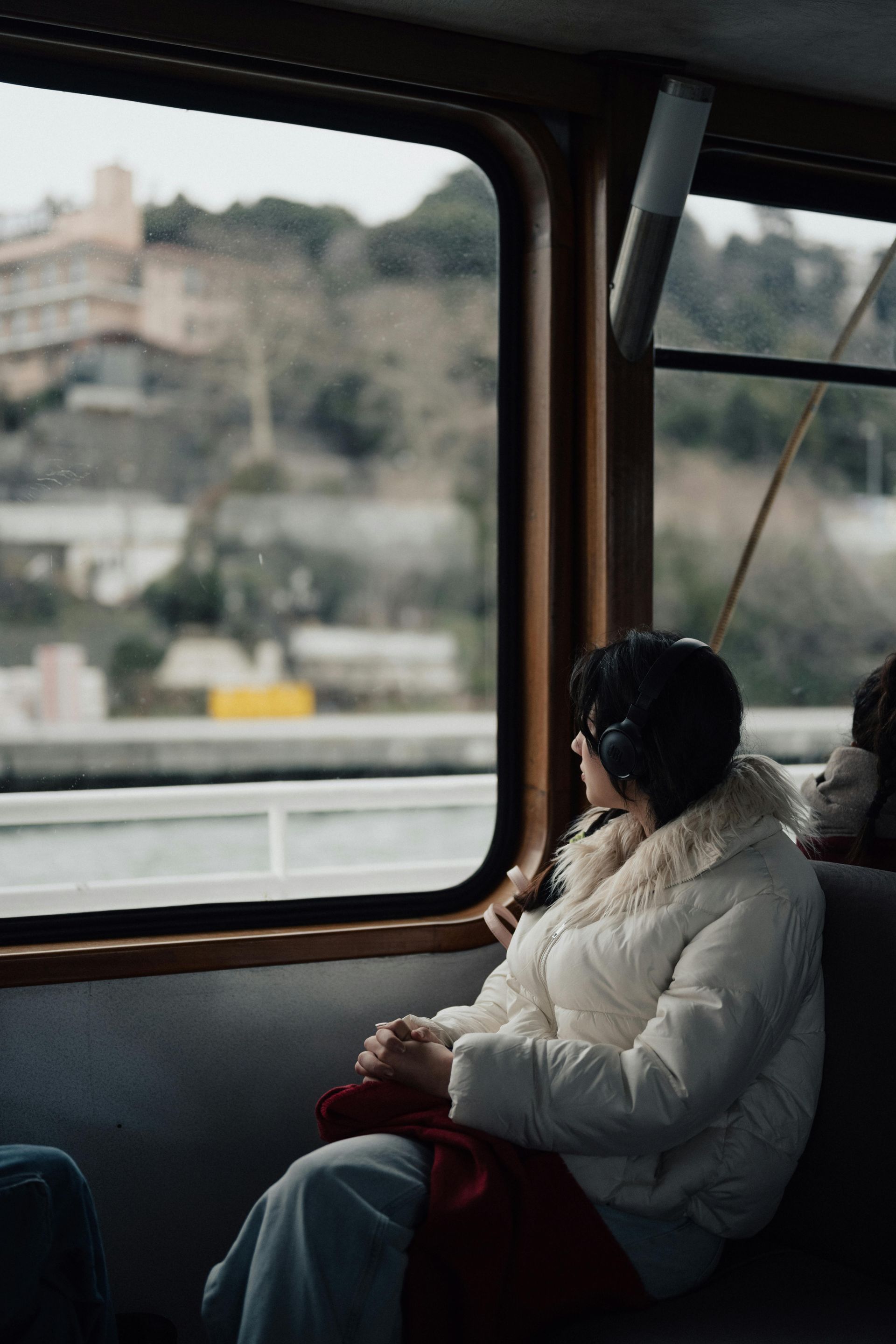 A woman is sitting on a bus looking out the window.