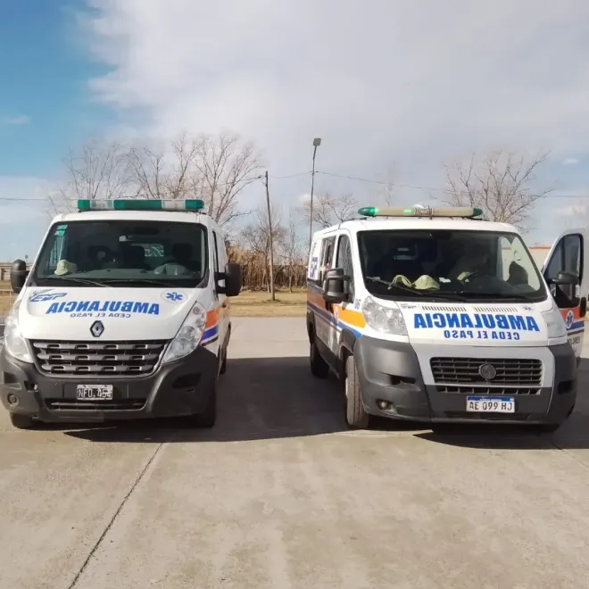 Dos ambulancias blancas estacionadas una al lado de la otra en una carretera bajo un cielo despejado.