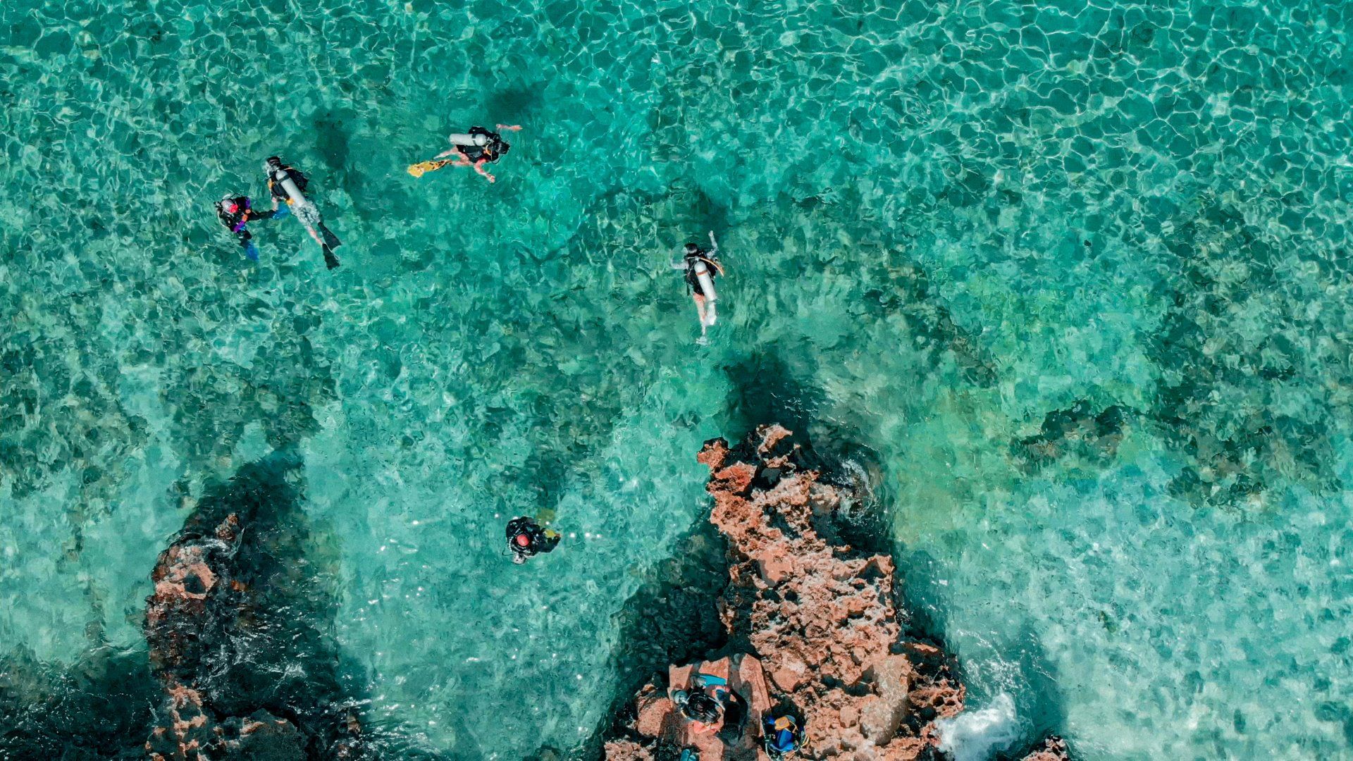 Vista aérea de personas nadando en mar turquesa entre rocas, un plan en San Andrés.