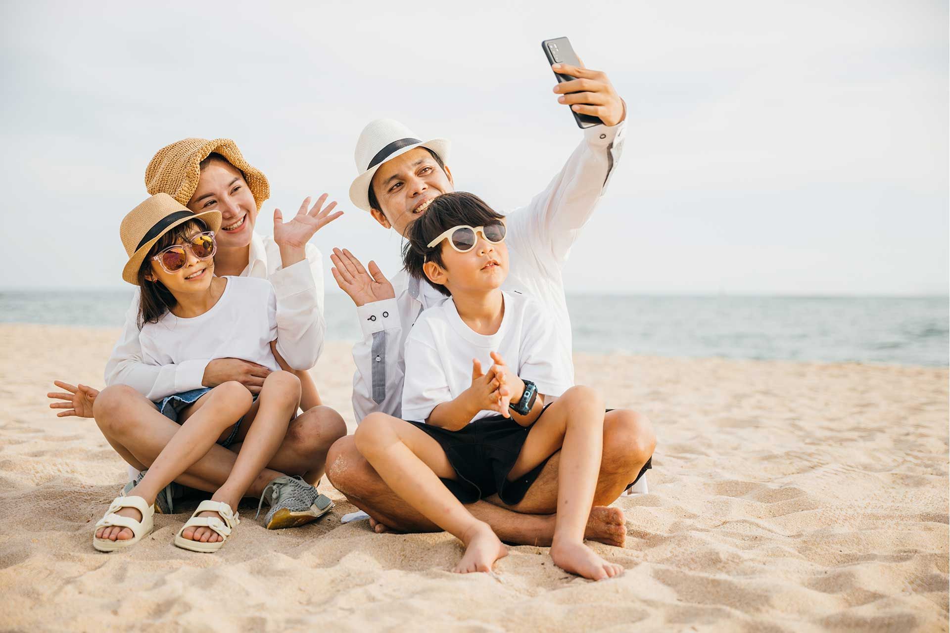 Familia sentada sobre la arena y sonriendo frente al mar, escena de San Andrés en familia para viajar con niños.