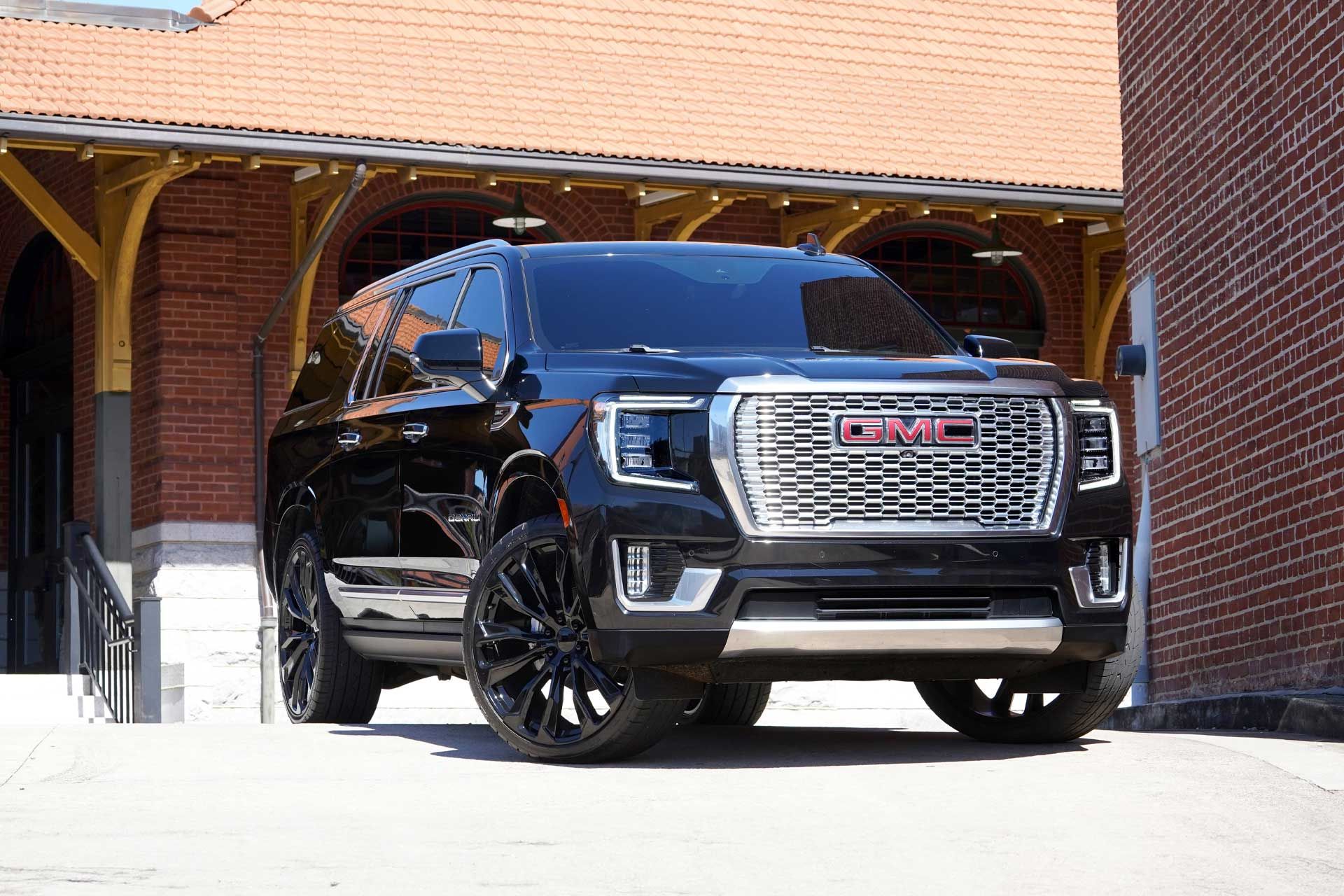Black GMC SUV parked under a brick carport, front view.