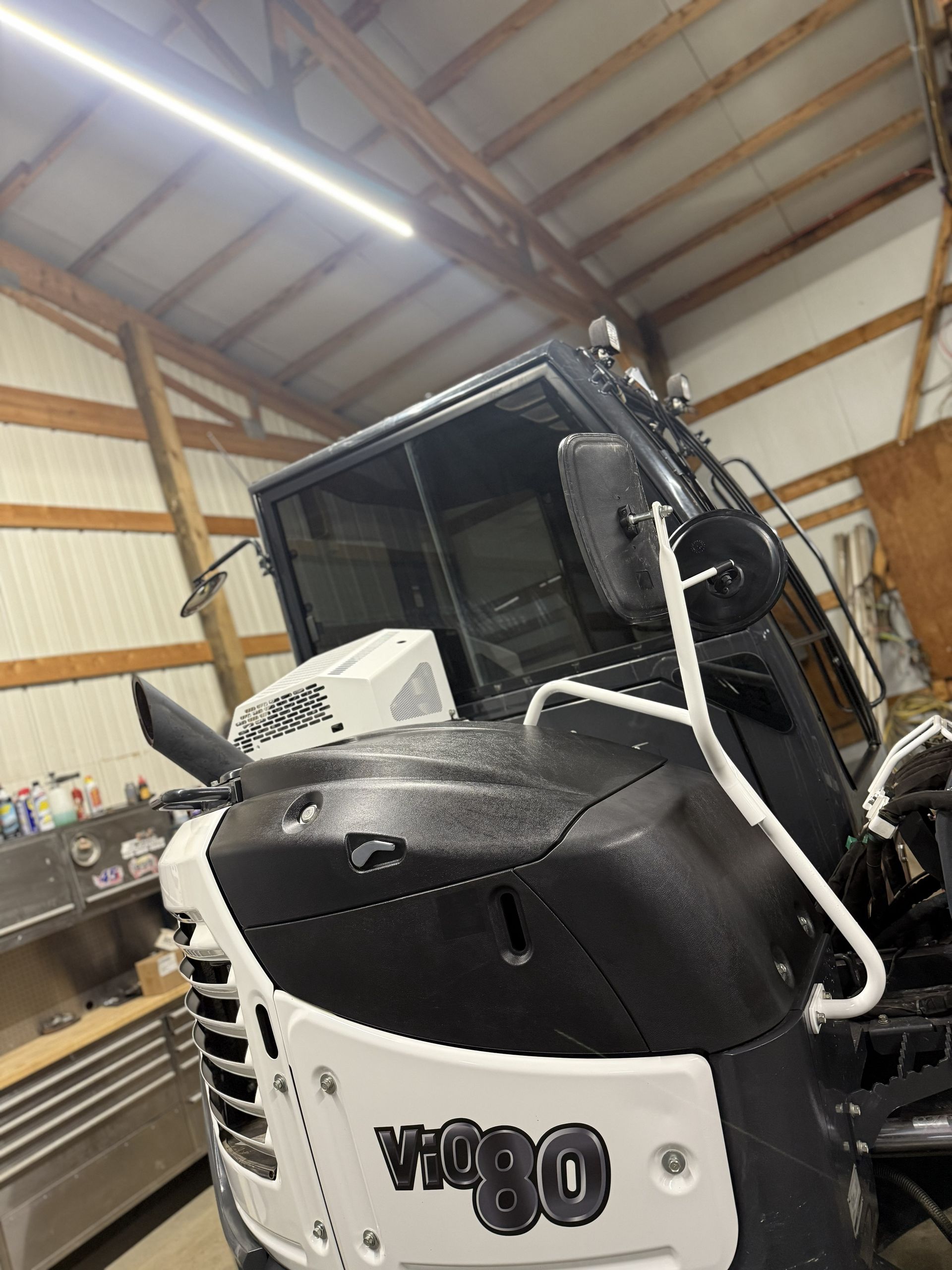 Black and white Bobcat V80 skid-steer loader inside a workshop garage