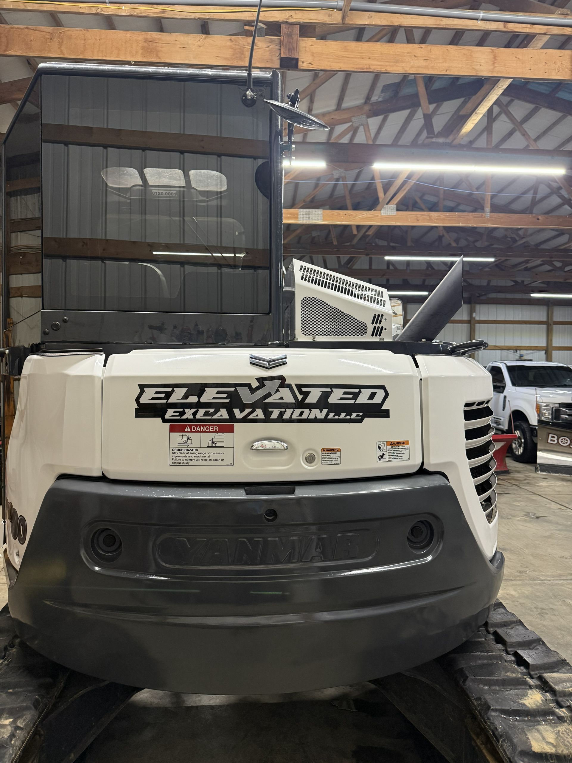 White scooter with “Elevated EV” branding parked inside a warehouse or garage, rear view