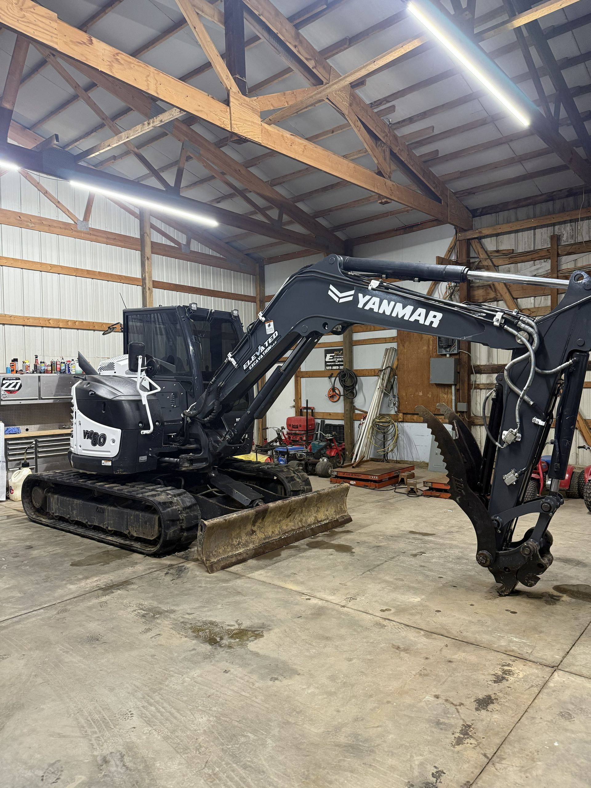 Black Yamaha mini excavator inside a warehouse with wood-framed walls and concrete floor