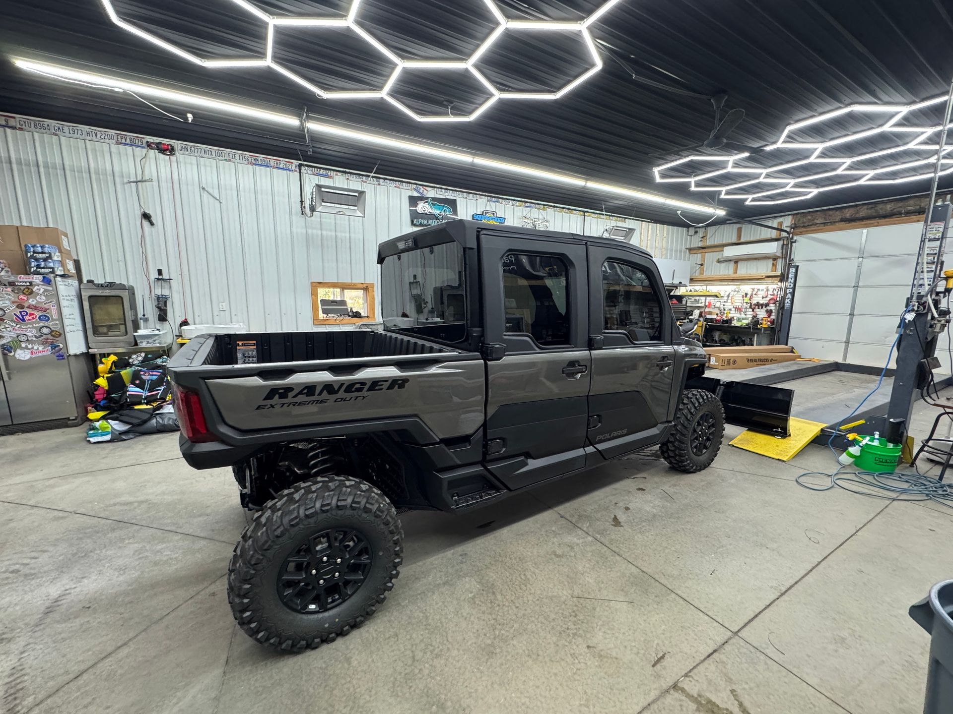Black off-road pickup truck in a garage with bright geometric ceiling lights