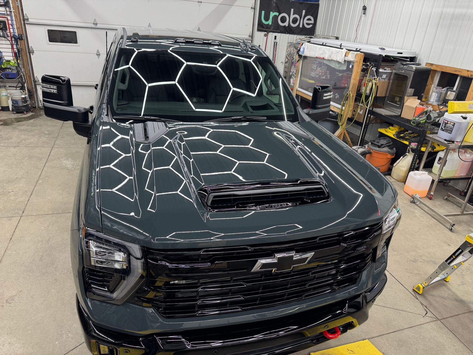 Dark gray pickup truck in a garage, with reflective lights on the windshield and hood scoop visible
