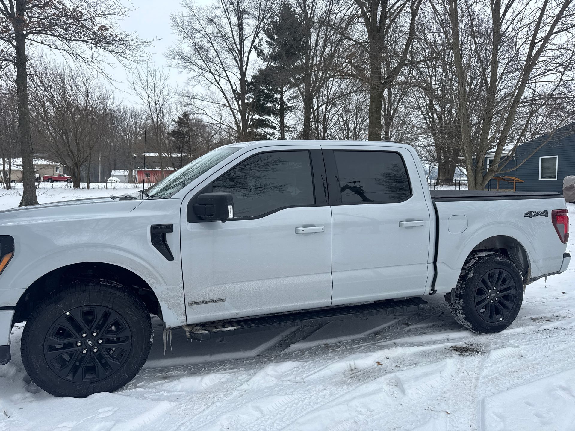 White pickup truck parked in a snowy lot with black wheels and tinted windows
