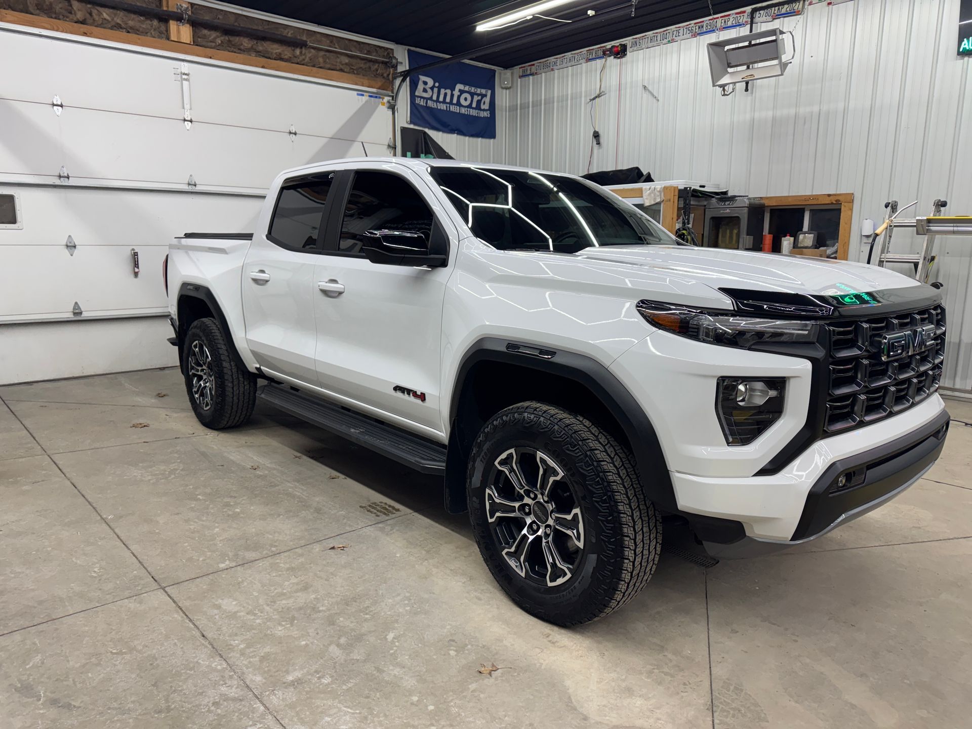 White pickup truck parked inside a garage or auto shop, front-left view