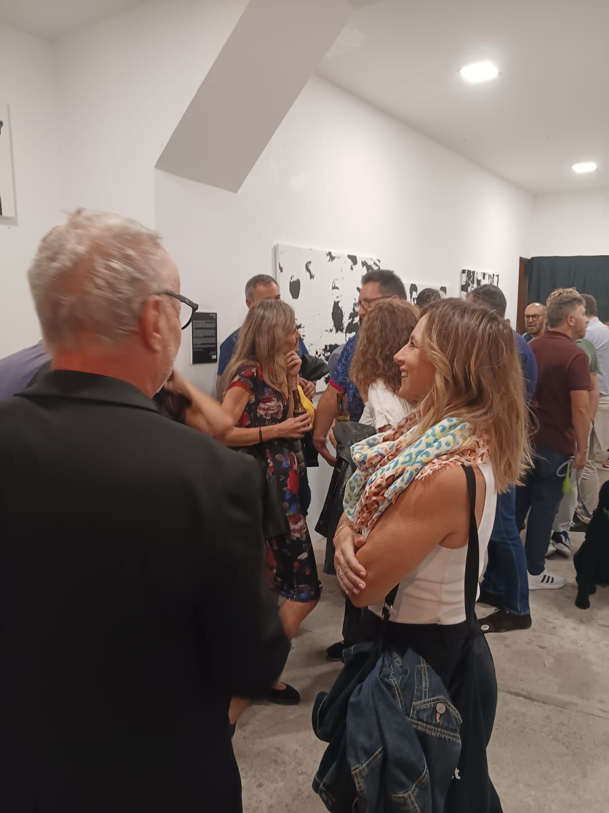 Un grupo de personas están de pie en una galería hablando entre sí.