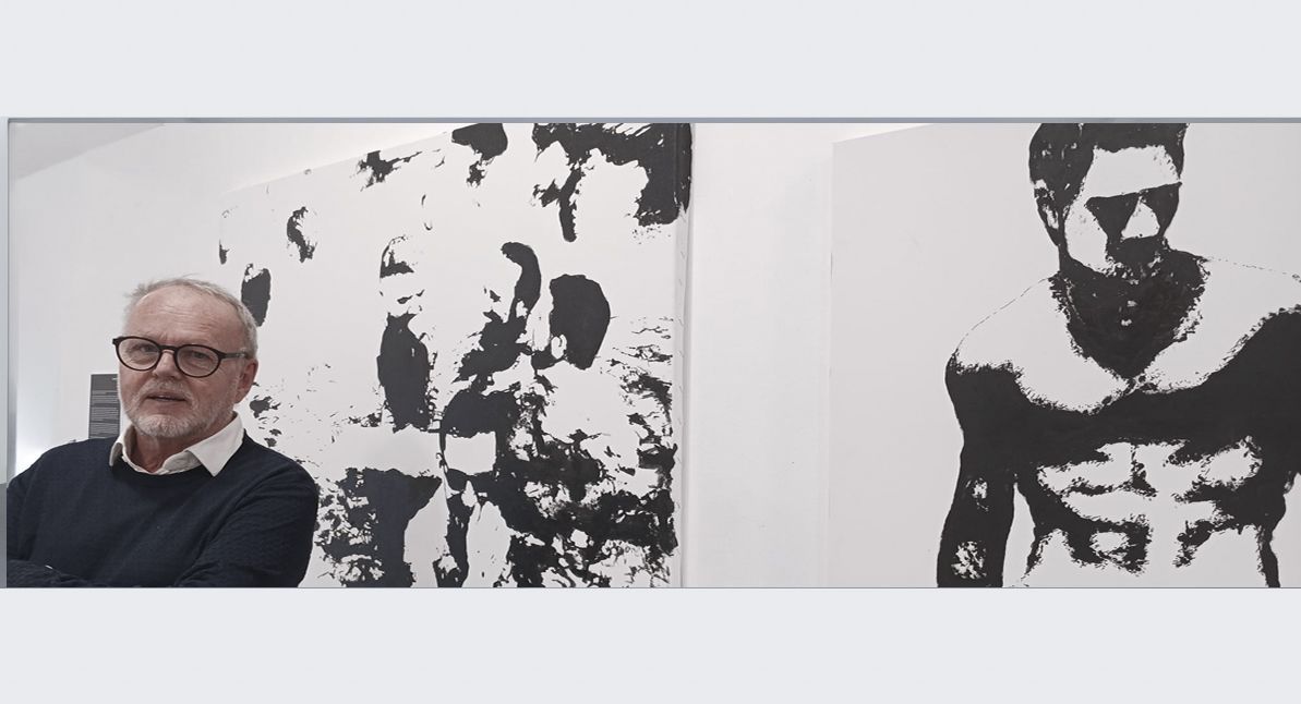 Spanish artist Daniel Garbade beside two black-and-white portrait artworks 