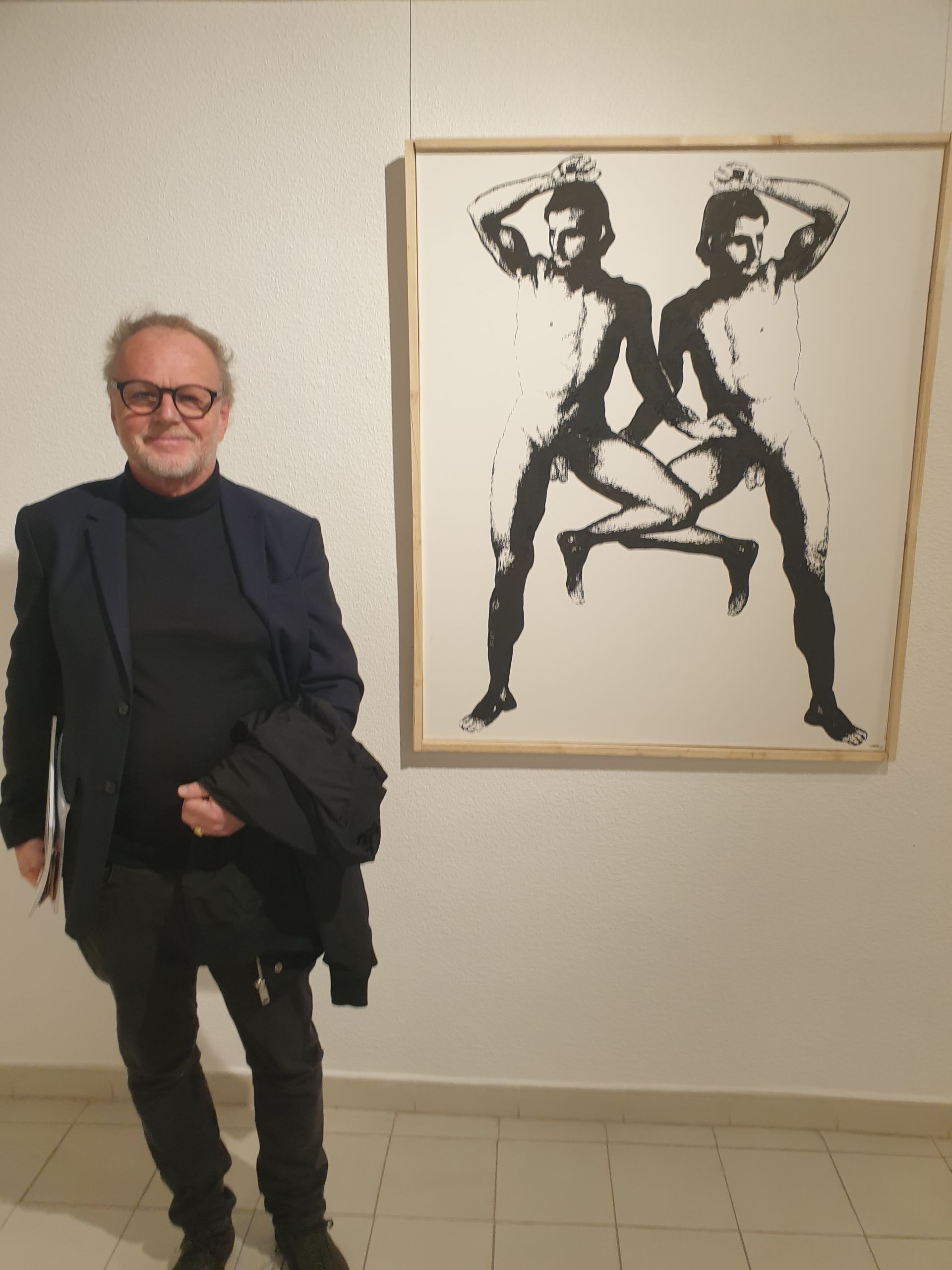 a man standing in front of a painting of two people