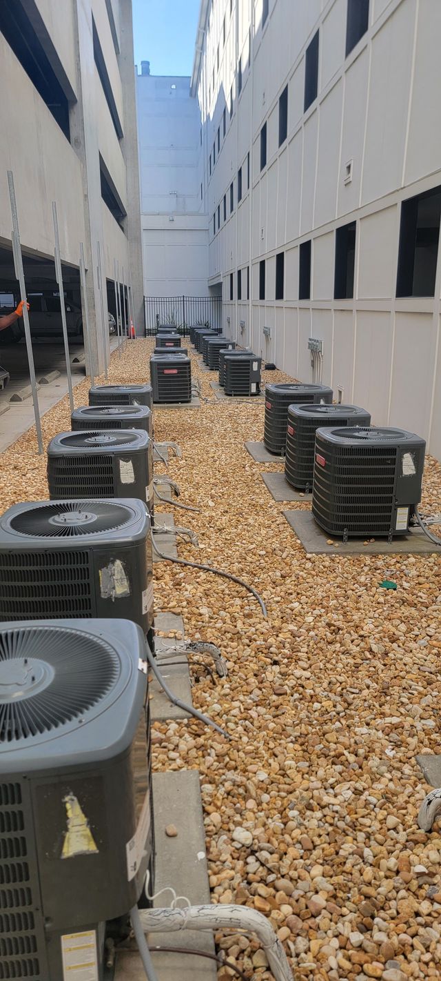 Technician repairing outdoor air conditioner unit with exposed wiring and tools