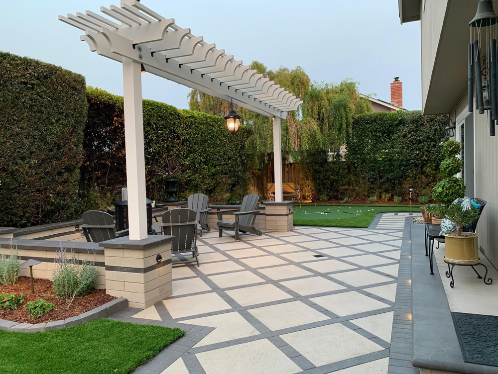A patio with a pergola and chairs in a backyard