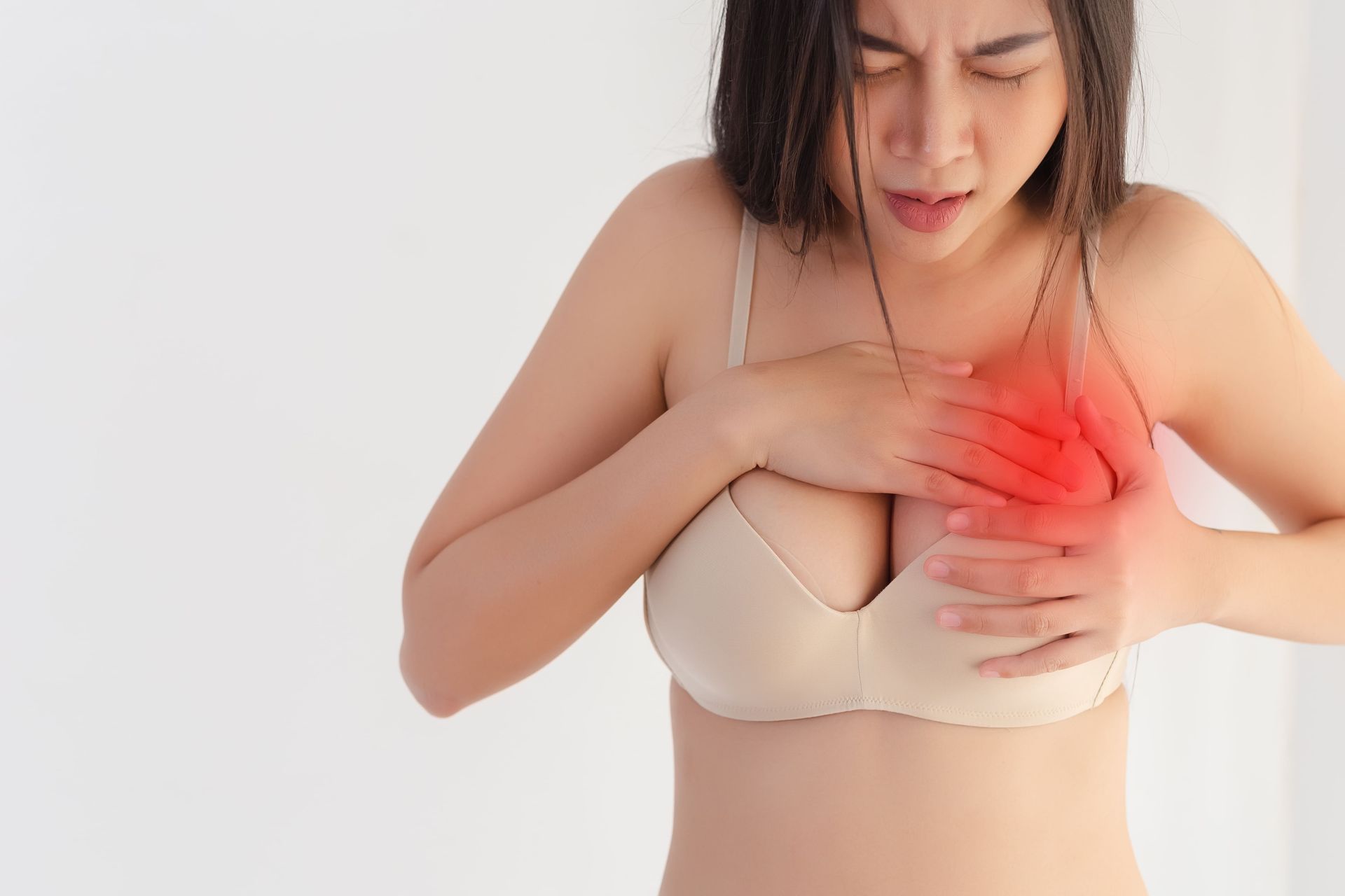 Mulher usando sutiã, segurando a região do seio com expressão de desconforto, ilustração de sintomas de contratura capsular