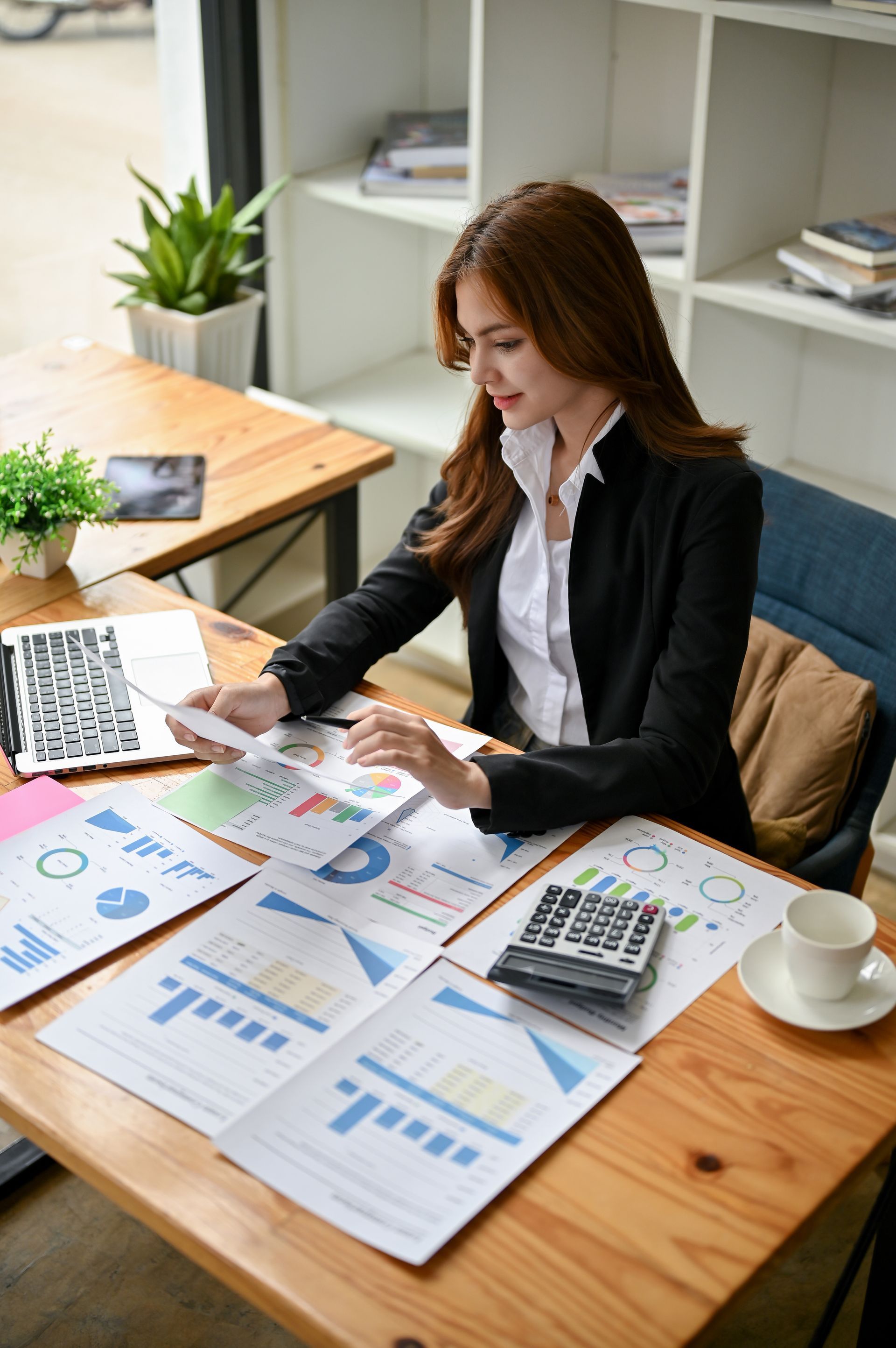 a woman is sitting at a table with papers and a laptop .