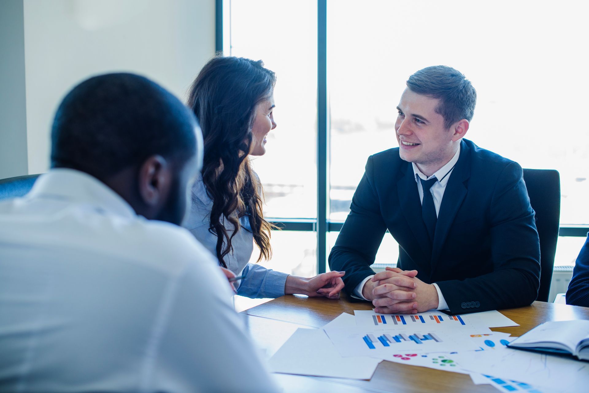 a group of business people are sitting at a table having a meeting .
