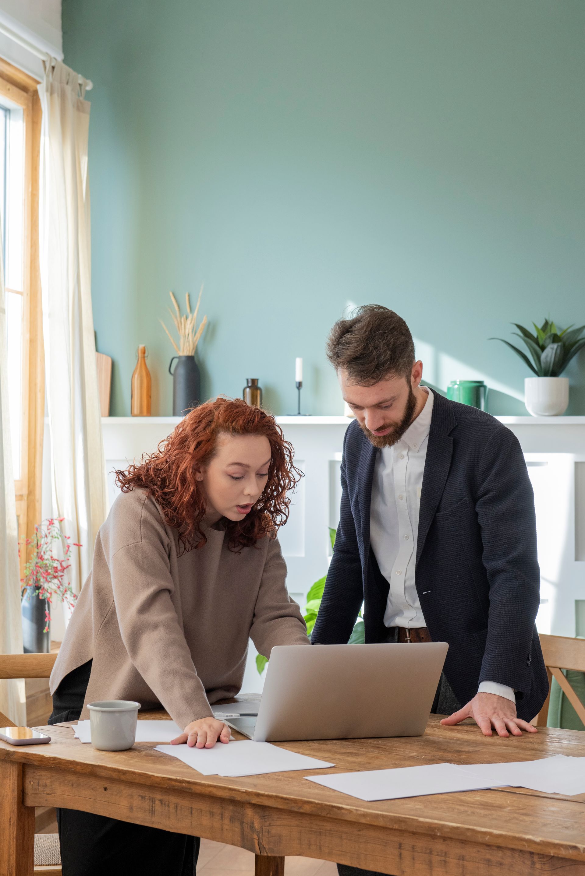 a man and a woman are sitting at a table looking at a laptop .