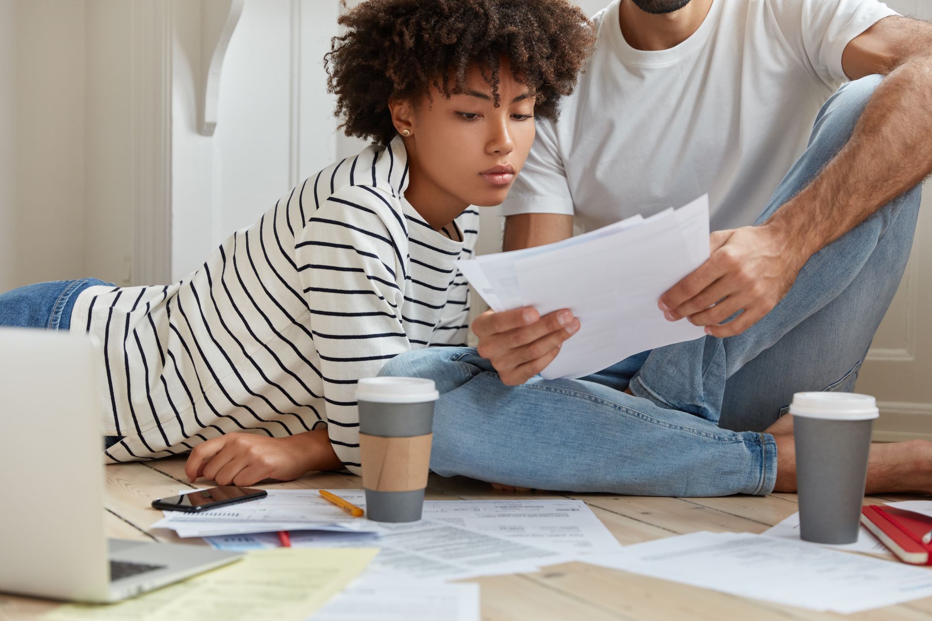 a man and a woman are sitting on the floor looking at papers .