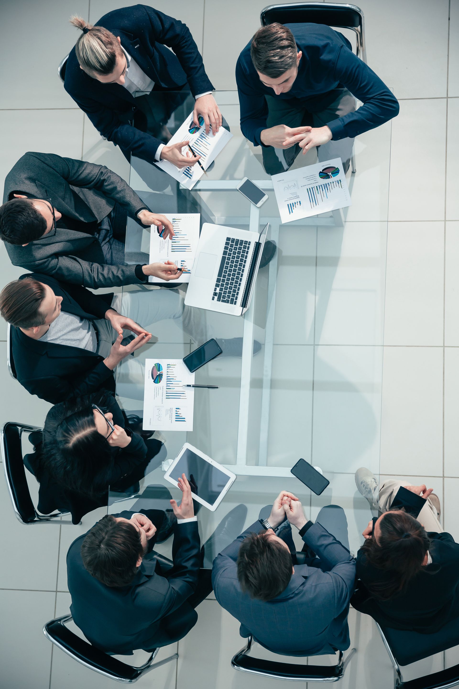 a group of business people are sitting around a table having a meeting .
