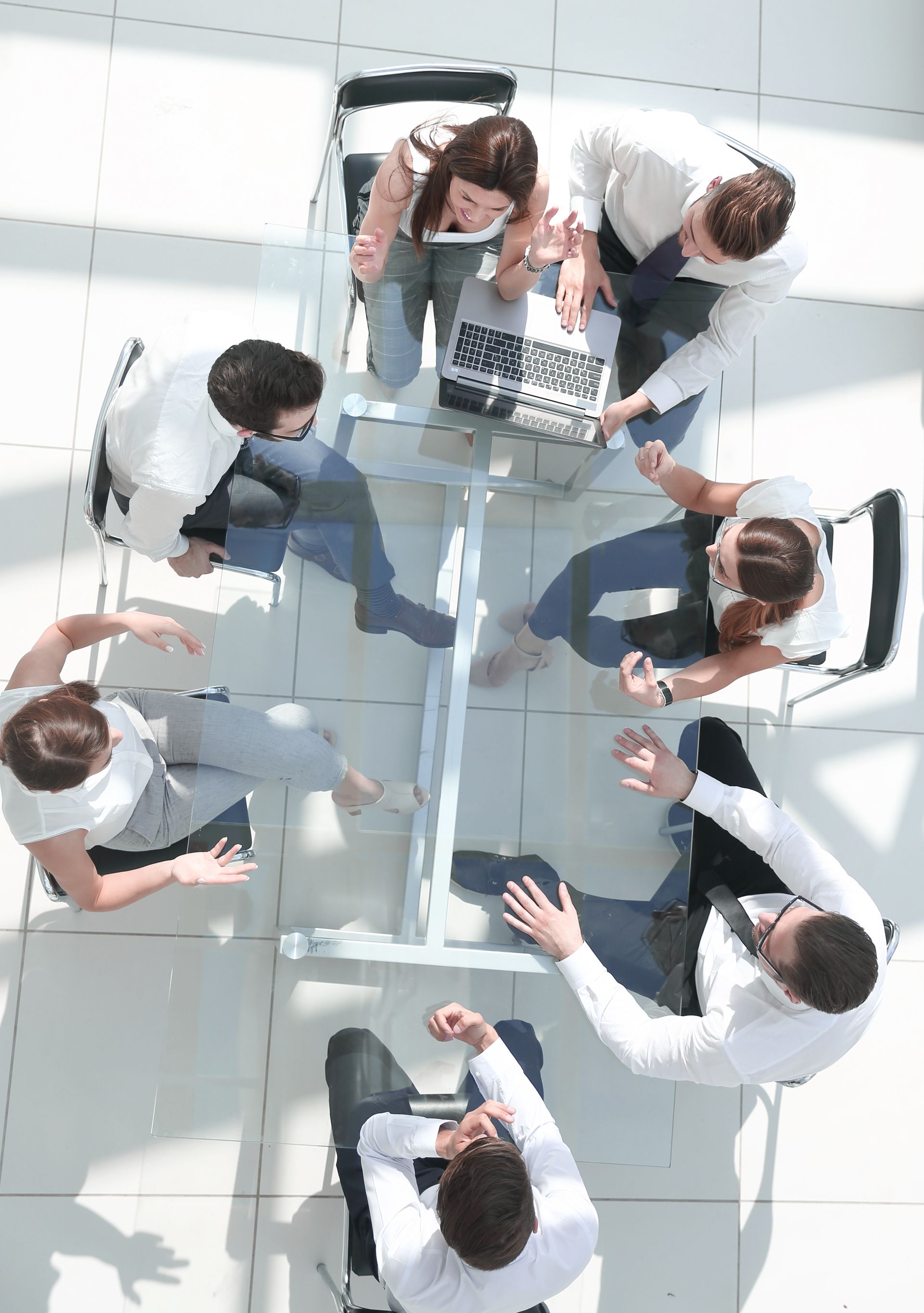 a group of people are sitting around a table with a laptop .