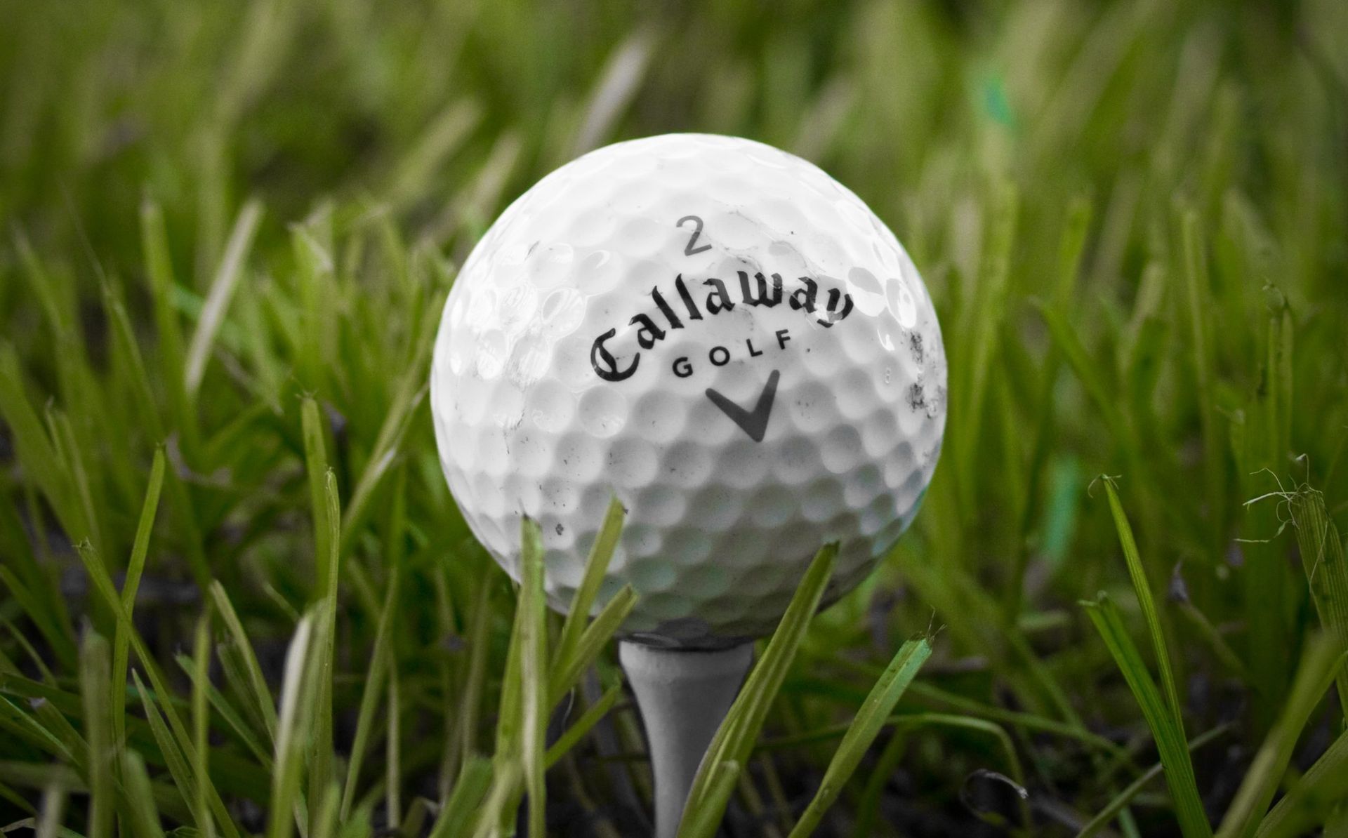 A golf ball is sitting on a tee in the grass.