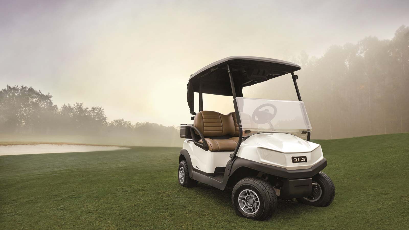A white golf cart is parked on a golf course.