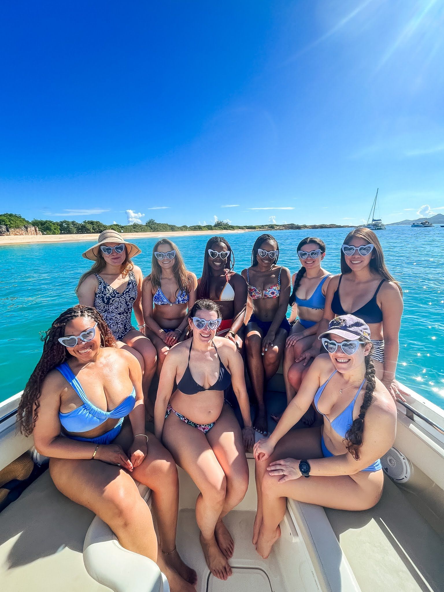 A group of women in bikinis are sitting on a boat in the ocean.
