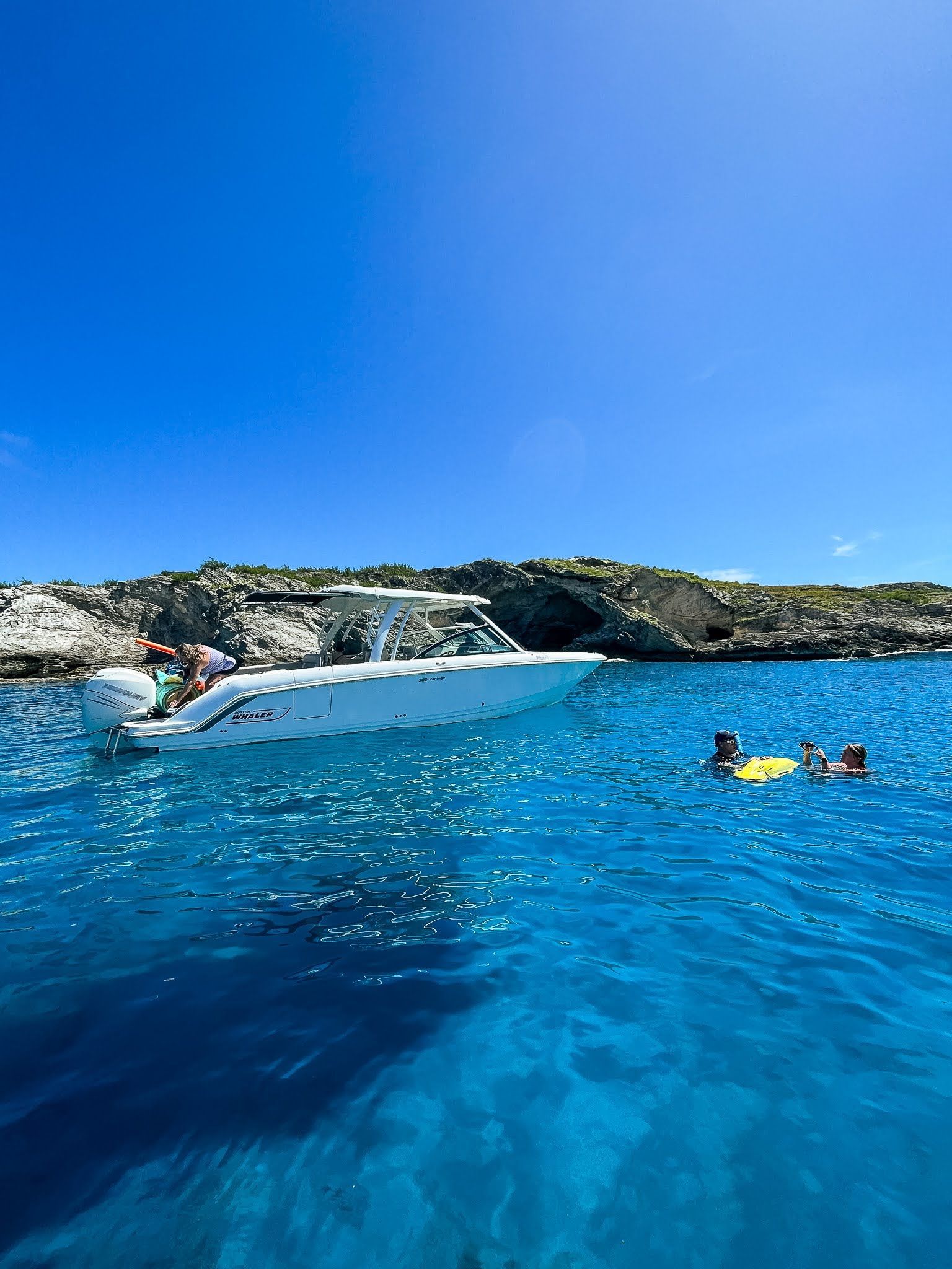 A group of people are swimming in the ocean next to a boat.