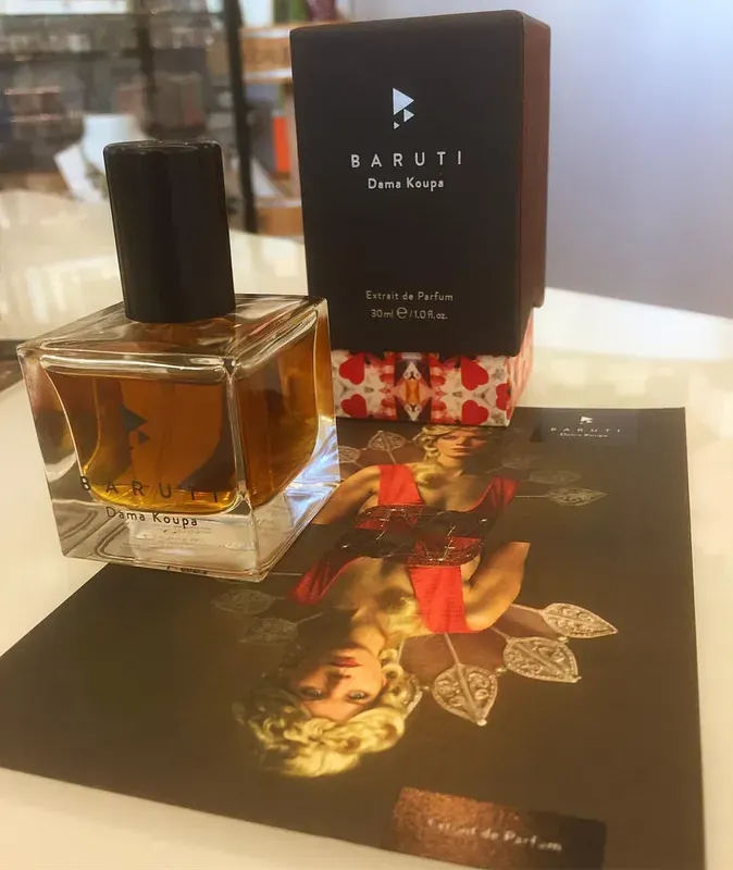 Flacone di profumo accanto a una scatola nera BARUTI e cartoncino illustrato su un tavolo