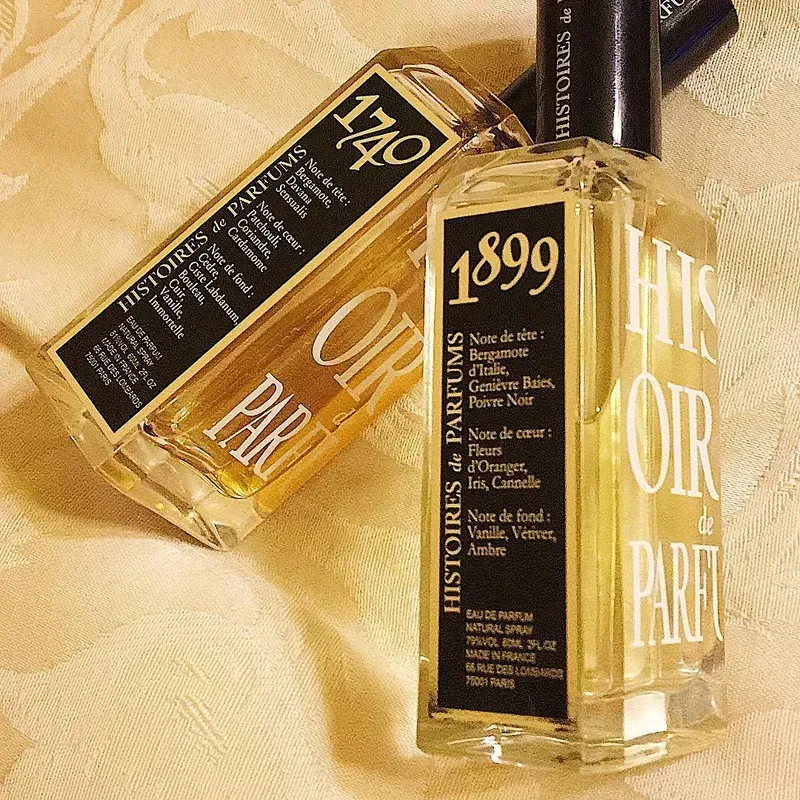 Due flaconi di profumo color ambra con tappi neri su uno sfondo di tessuto beige.