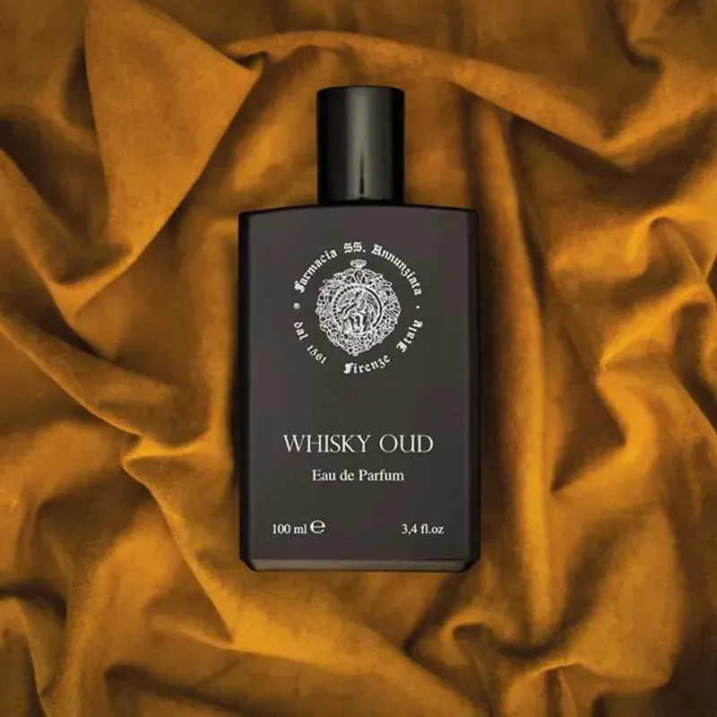 Flacone di eau de parfum Whisky Oud su sfondo di tessuto satinato dorato.