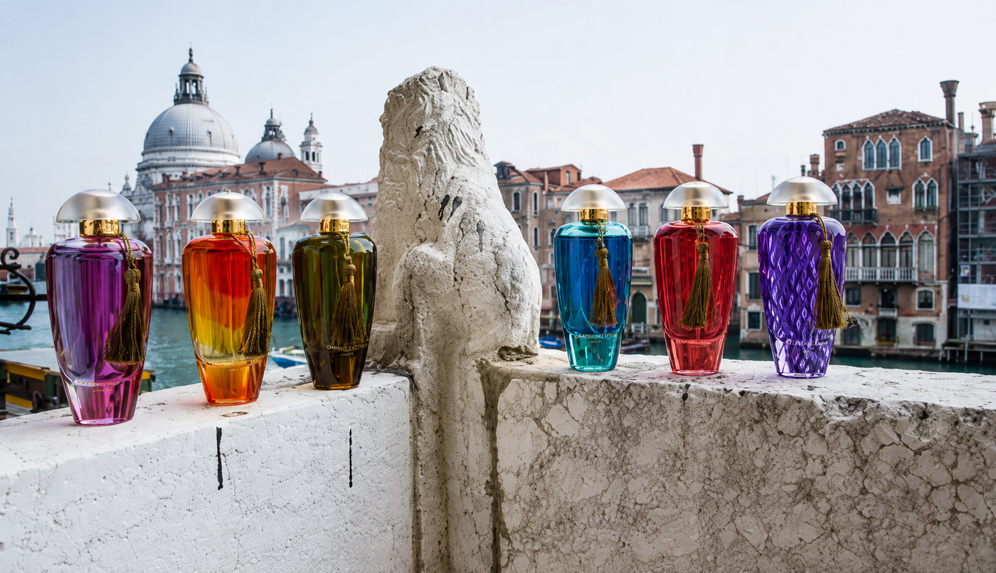 Vasi di vetro colorati allineati su una sporgenza di pietra che si affaccia su un canale e sugli edifici della città.