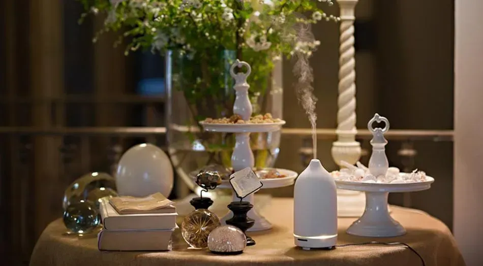 Elegante allestimento da tavola con vasi, ciotole e dettagli in vetro in ceramica bianca, su una tovaglia color beige.