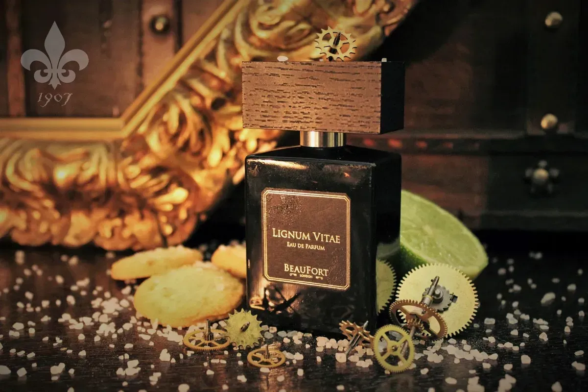 Flacone di profumo con tappo dorato su un tavolo scuro, circondato da fette di agrumi e oggetti decorativi sparsi.