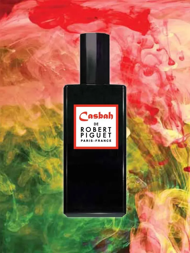 Flacone di profumo nero con logo Robert Piguet su uno sfondo astratto colorato rosso, giallo e verde.