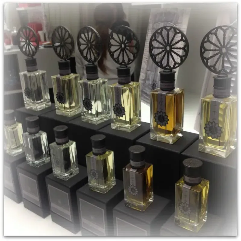 Flaconi di profumo esposti su scaffali, con tappi decorativi a forma di ruota e contenenti liquidi trasparenti