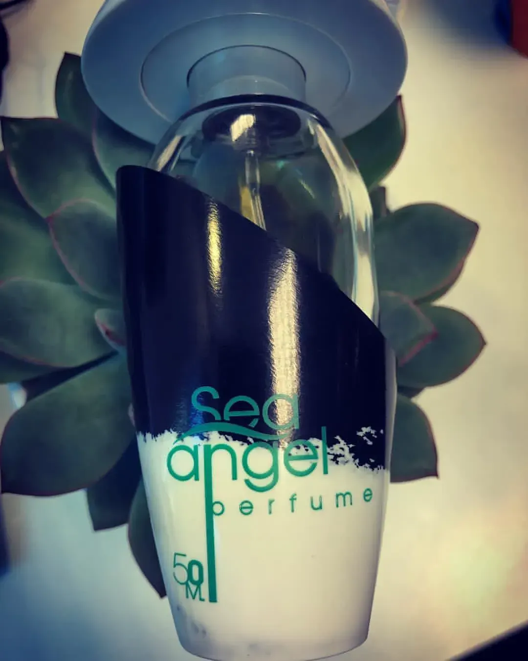 Flacone di profumo Scent Angel con etichetta blu scuro e bianca su sfondo a forma di fiore.