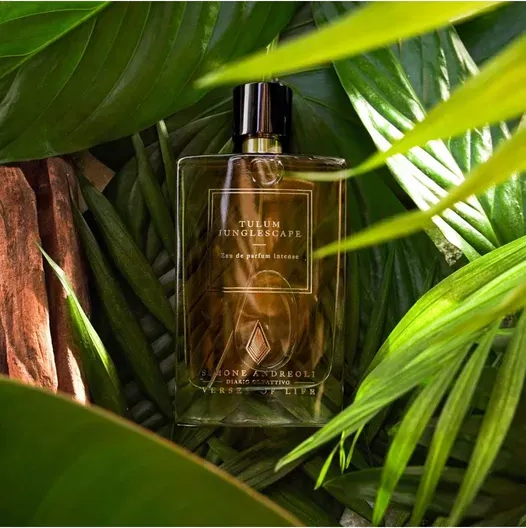 Una boccetta di profumo color ambra tra lussureggianti foglie di palma verde.
