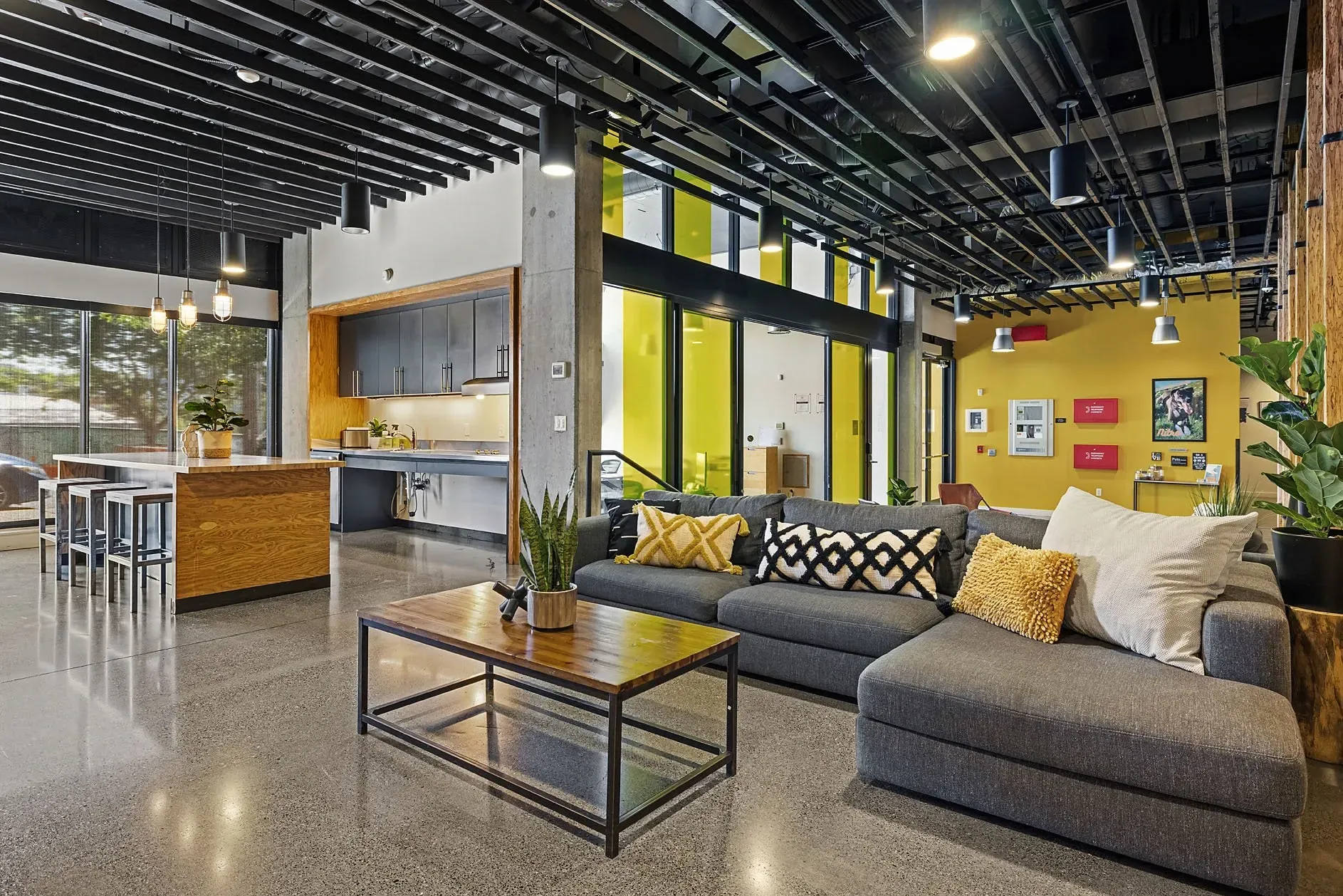 Modern lounge area with a sectional sofa, coffee table, and a kitchen island with bar stools.