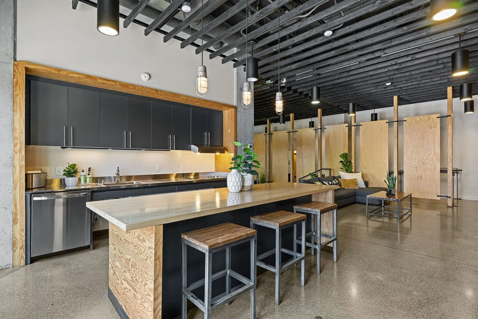 Modern kitchen island with bar stools and a lounge area with a sectional sofa.