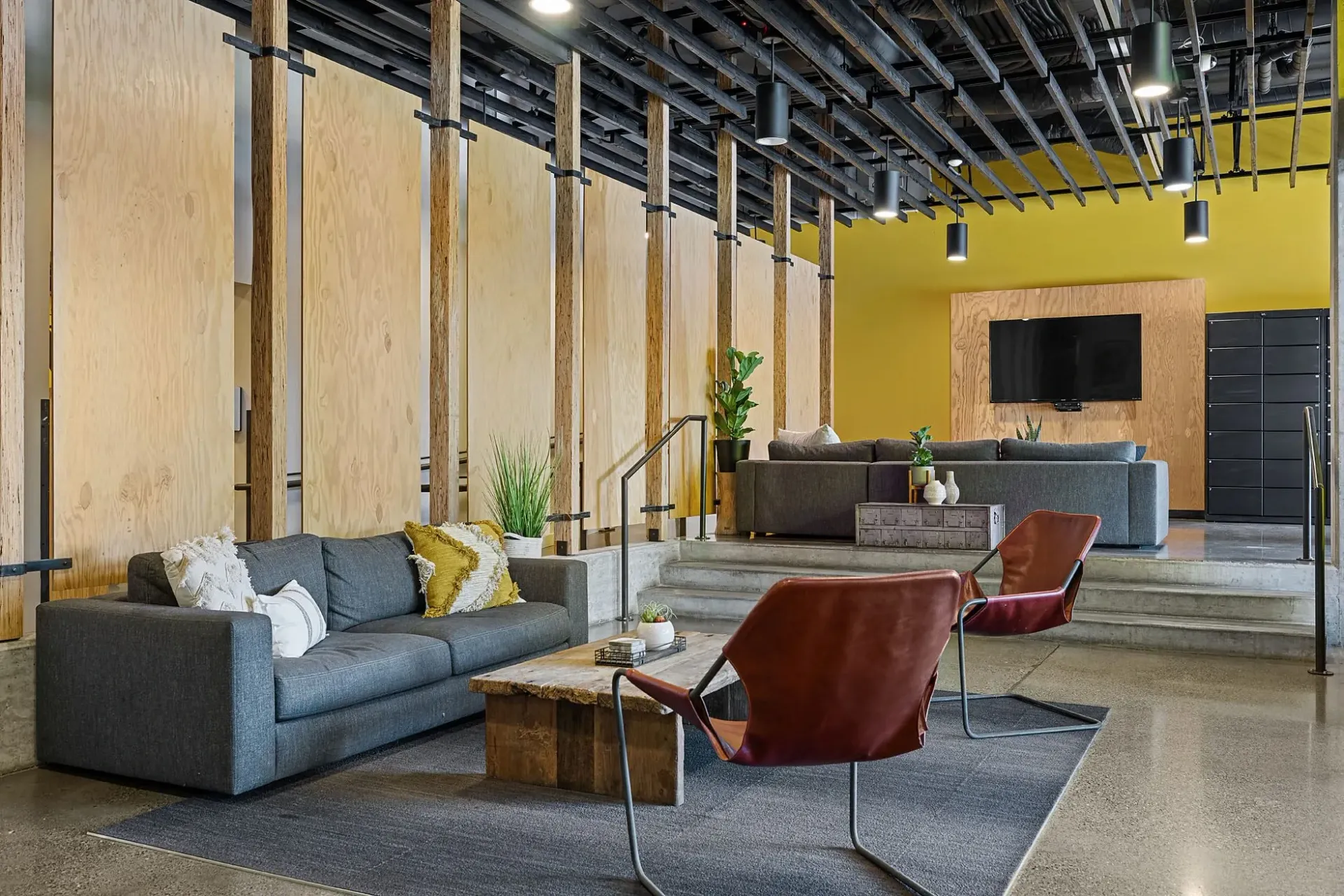 Modern lounge area with sofas, chairs, coffee table, and television.