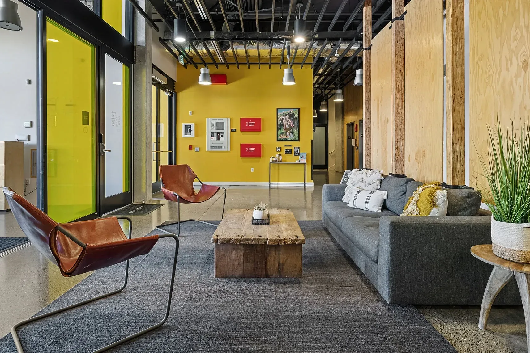 Modern lobby with yellow accent wall, leather chairs, and a gray sofa.