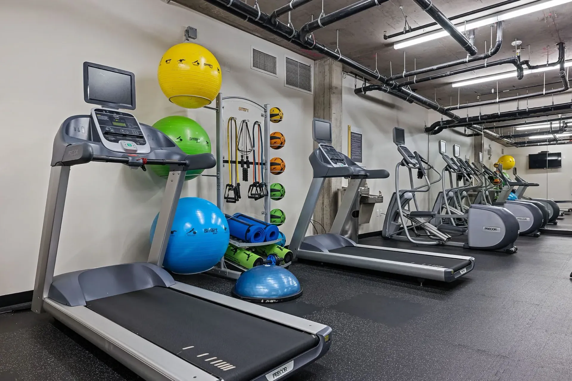 Treadmills and elliptical machines in a well-equipped apartment gym.