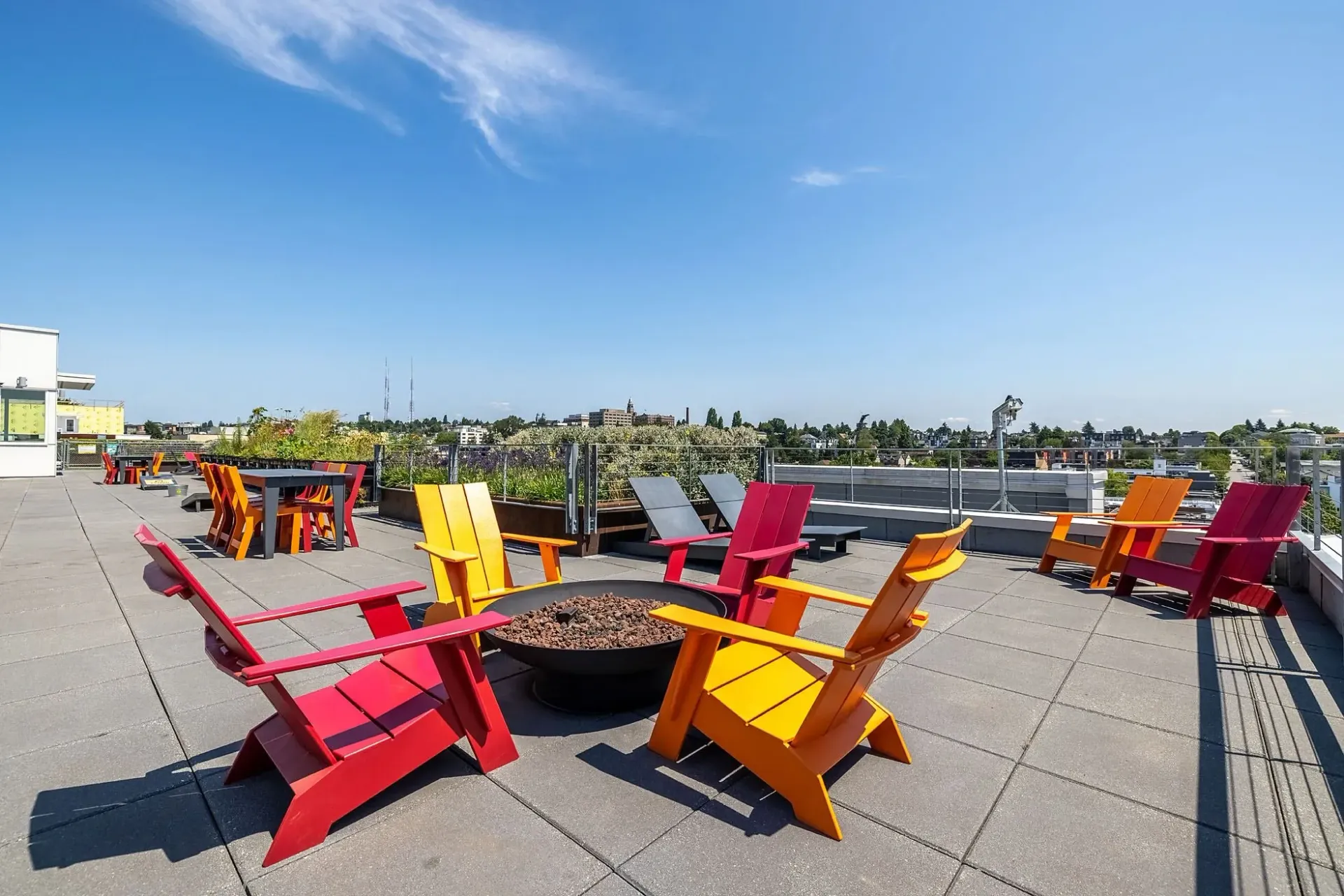 Rooftop patio with colorful chairs and fire pit with city view.