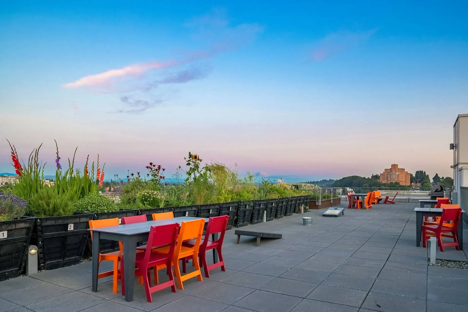 Rooftop patio with tables and chairs overlooking the city at sunset.