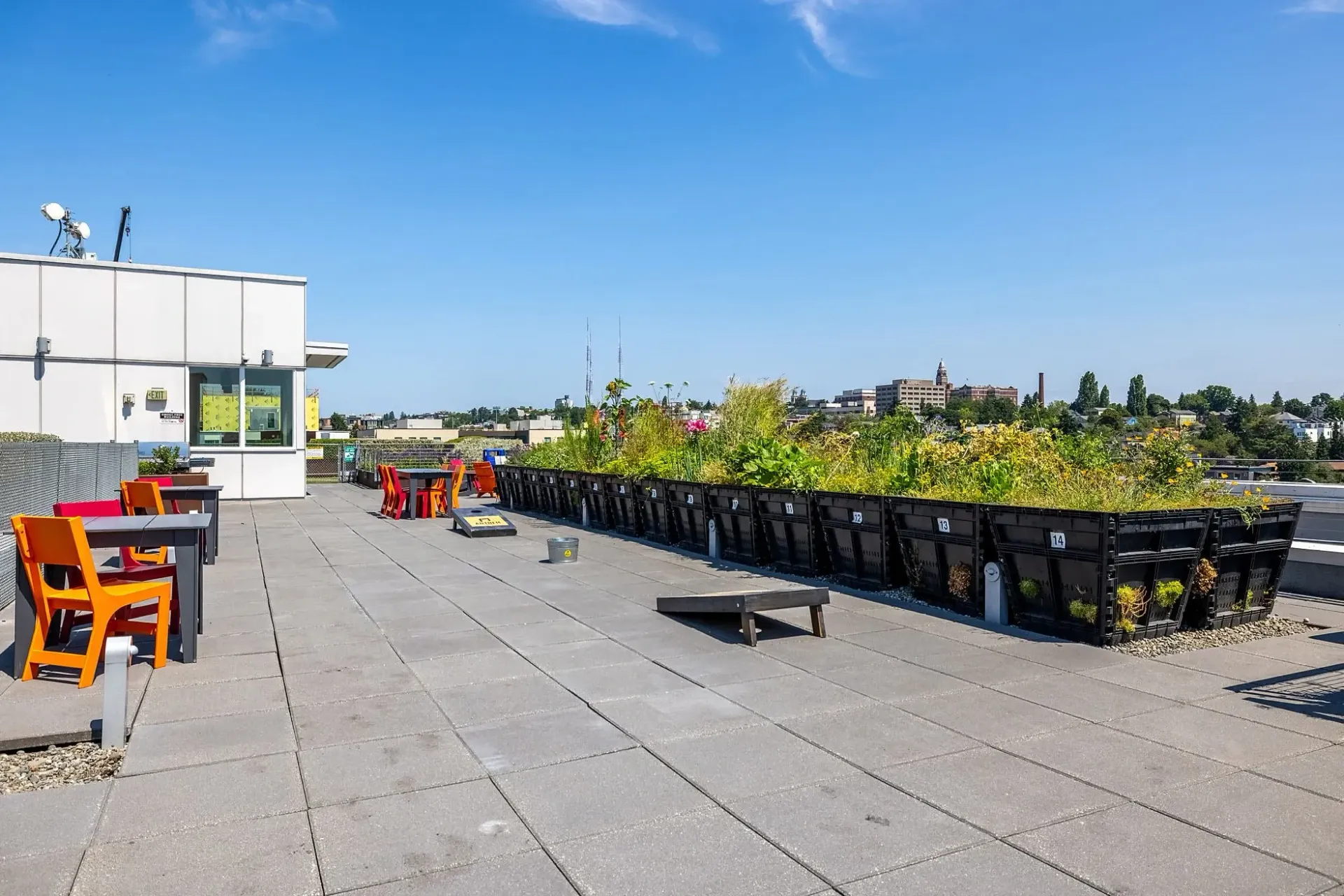 Rooftop terrace with seating, garden beds, and city views.