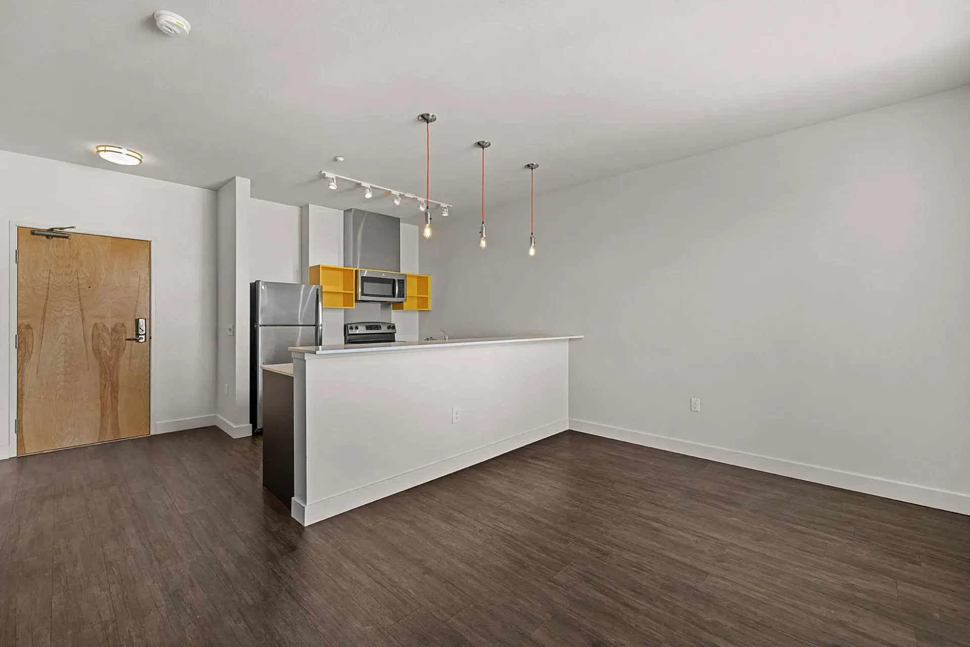 Interior view of an apartment showing a kitchen area with stainless steel appliances and a living area.