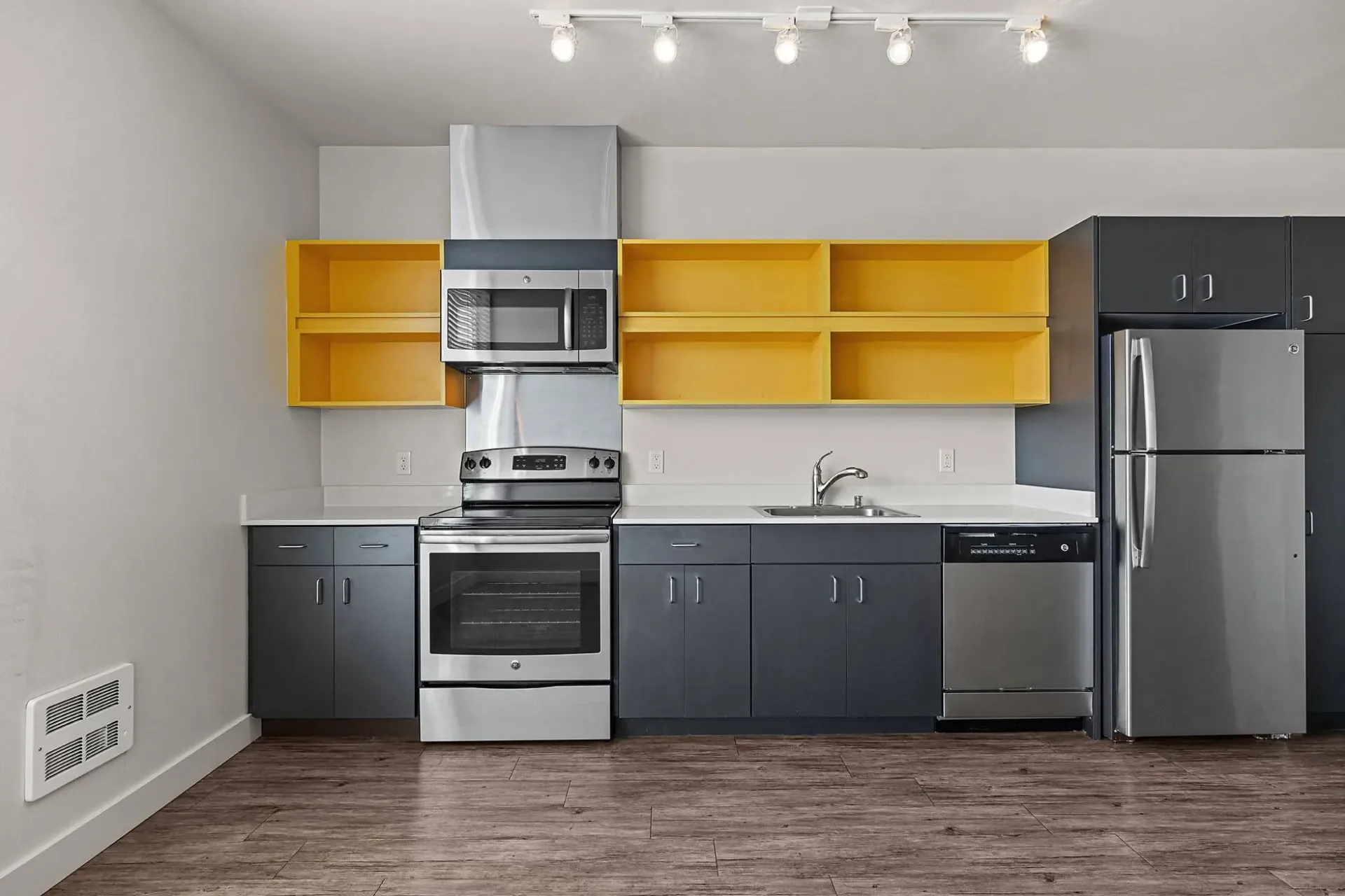 Modern kitchen with stainless steel appliances and dark gray cabinets.